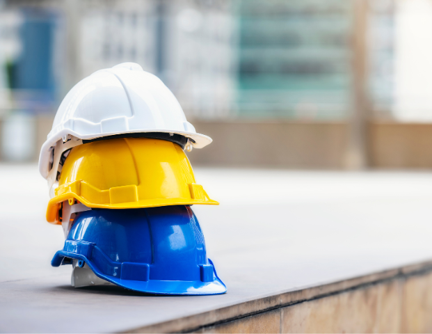 three hard hats, white, yellow, and blue, stacked on top of one another